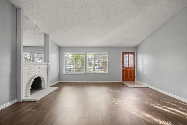 unfurnished living room with a fireplace, dark hardwood / wood-style floors, and a textured ceiling