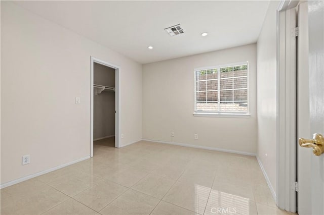 unfurnished bedroom with light tile patterned floors, a walk in closet, and a closet