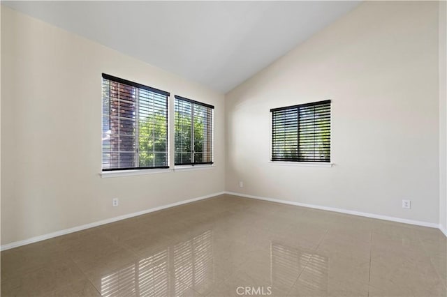 tiled spare room featuring lofted ceiling