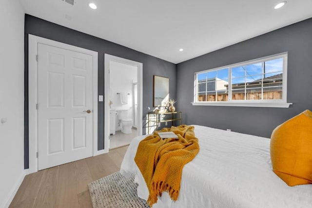 bedroom with ensuite bath and light hardwood / wood-style floors