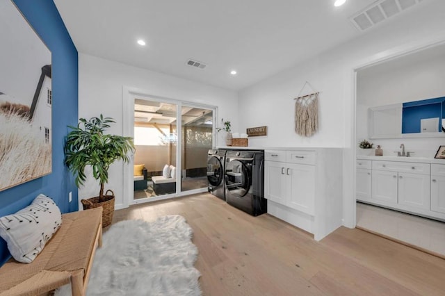 interior space with sink, washer and clothes dryer, cabinets, and light wood-type flooring