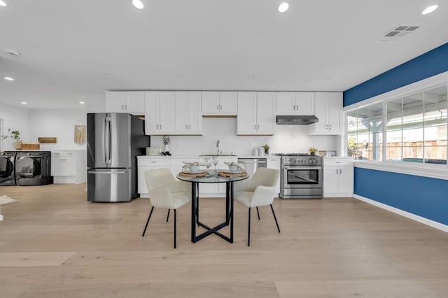 kitchen featuring stainless steel appliances, washing machine and dryer, sink, and white cabinets