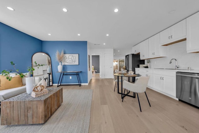 kitchen featuring white cabinetry, dishwasher, black refrigerator, and sink