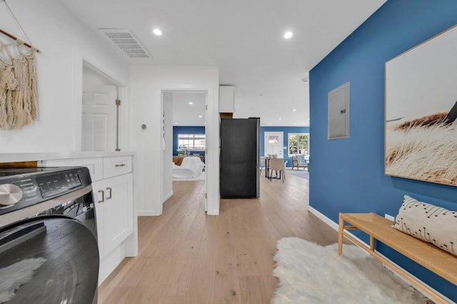 interior space with washer / clothes dryer, electric panel, and light hardwood / wood-style flooring