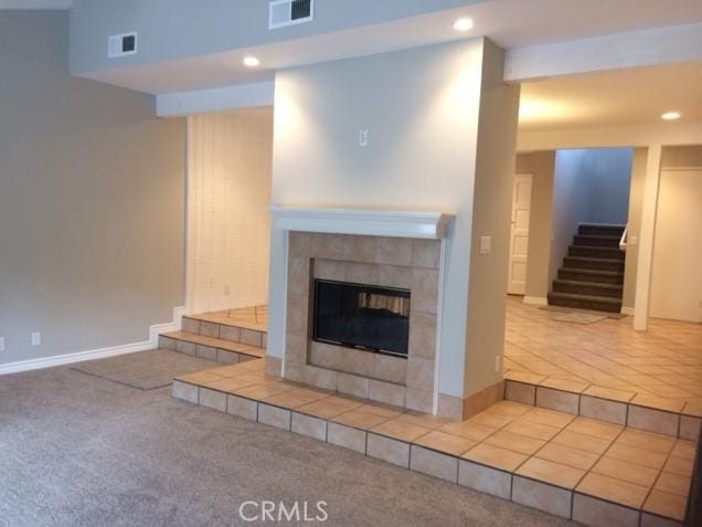 unfurnished living room with a tiled fireplace and carpet floors