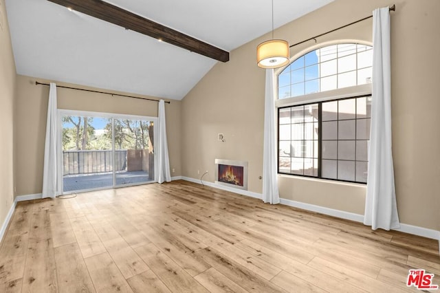 unfurnished living room with vaulted ceiling with beams and light wood-type flooring