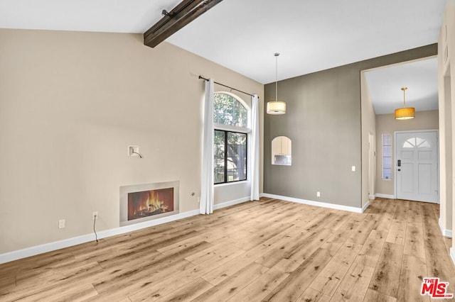 unfurnished living room with vaulted ceiling with beams and light wood-type flooring