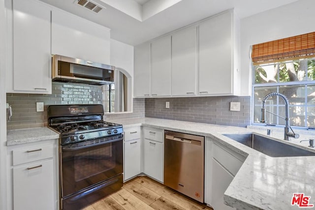 kitchen featuring white cabinetry, sink, light stone counters, and stainless steel appliances