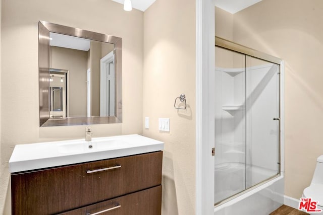 full bathroom featuring toilet, vanity, and bath / shower combo with glass door