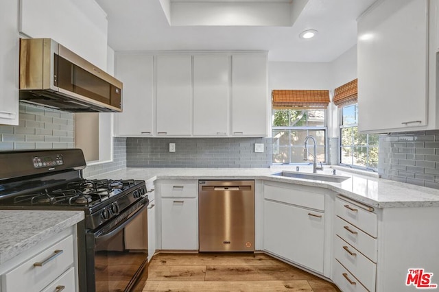 kitchen featuring sink, appliances with stainless steel finishes, light stone countertops, white cabinets, and light wood-type flooring