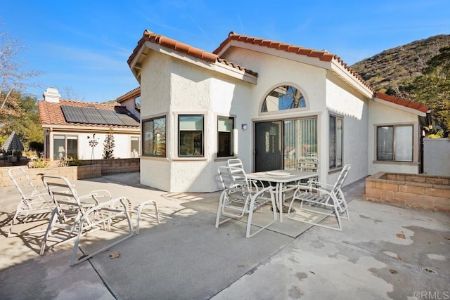 rear view of property featuring a mountain view, a patio area, and solar panels