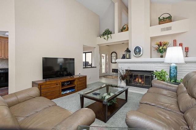 carpeted living room with a towering ceiling and a brick fireplace