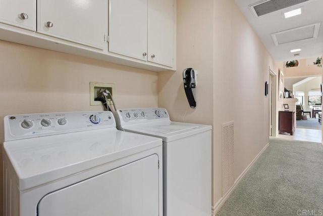 clothes washing area featuring light carpet, independent washer and dryer, and cabinets