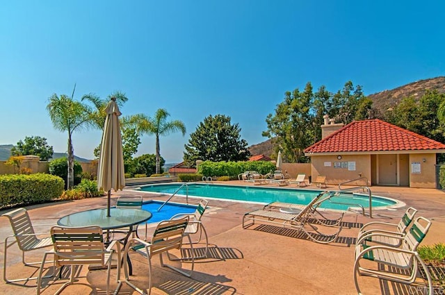 view of swimming pool with a hot tub, a mountain view, and a patio area