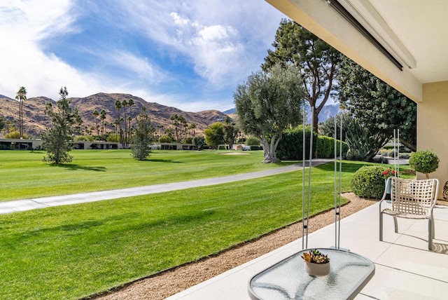 surrounding community featuring a mountain view, a lawn, and a patio area