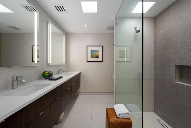 bathroom featuring vanity, a tile shower, tile patterned floors, and backsplash