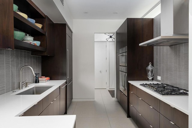 kitchen with wall chimney range hood, sink, appliances with stainless steel finishes, backsplash, and light tile patterned flooring