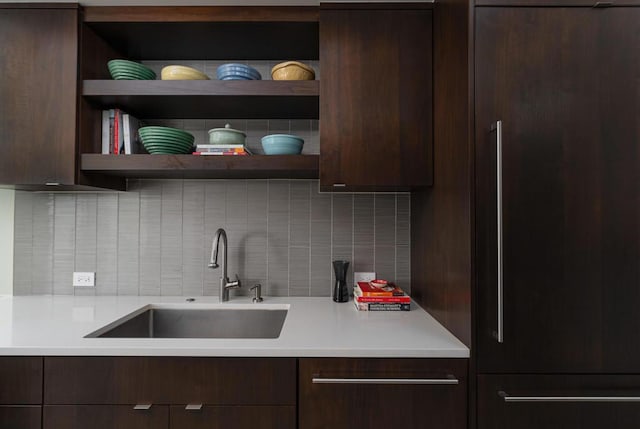 kitchen featuring paneled built in refrigerator, dark brown cabinets, sink, and backsplash