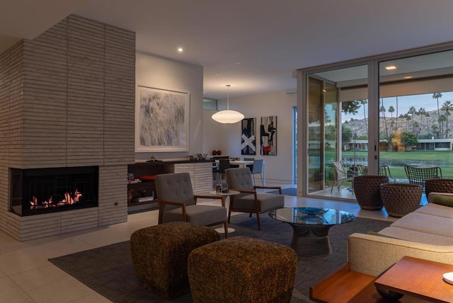 living room featuring a brick fireplace, light tile patterned floors, and expansive windows