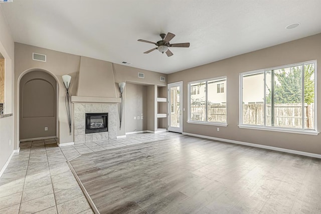 unfurnished living room featuring ceiling fan and a tile fireplace