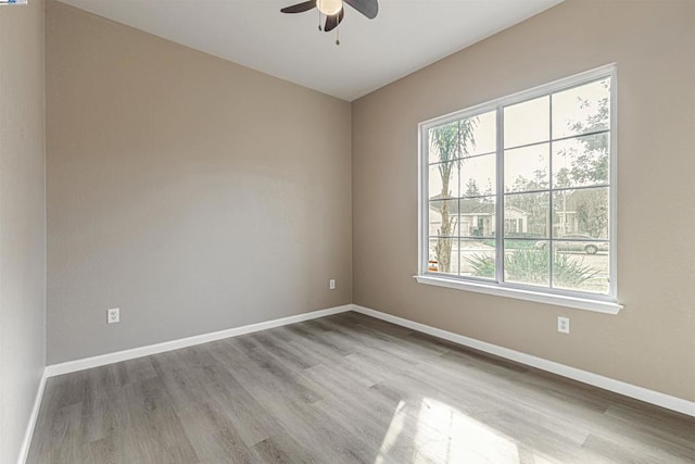 spare room featuring ceiling fan, a healthy amount of sunlight, and light wood-type flooring