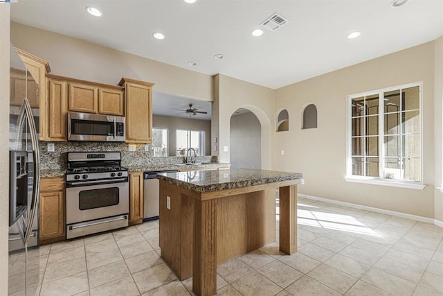 kitchen with sink, backsplash, a kitchen breakfast bar, dark stone counters, and stainless steel appliances