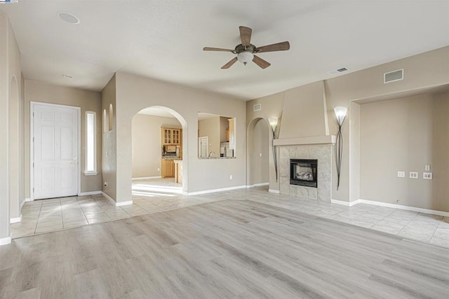 unfurnished living room featuring ceiling fan, a fireplace, and light hardwood / wood-style floors