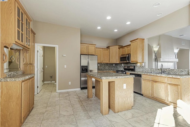 kitchen with a breakfast bar area, a kitchen island, stainless steel appliances, light stone countertops, and decorative backsplash