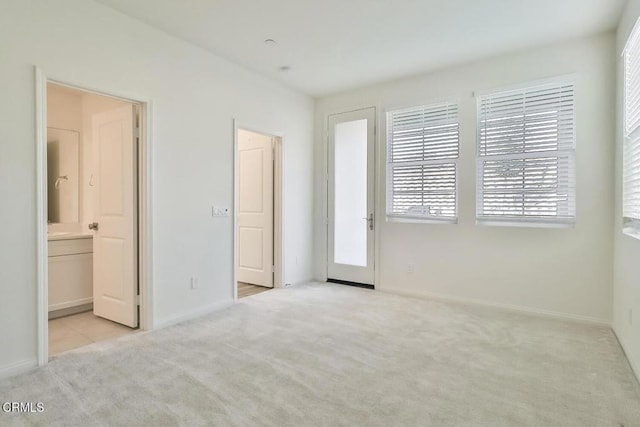 unfurnished bedroom with light carpet and connected bathroom