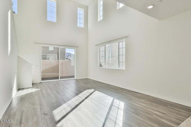 unfurnished living room featuring hardwood / wood-style flooring, a healthy amount of sunlight, and a high ceiling