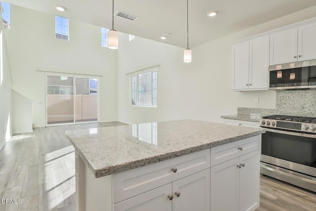 kitchen with white cabinetry, appliances with stainless steel finishes, hanging light fixtures, and backsplash