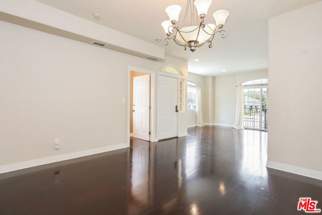 spare room featuring a notable chandelier and dark hardwood / wood-style flooring