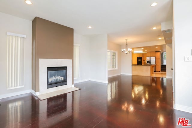 unfurnished living room with an inviting chandelier and dark hardwood / wood-style floors