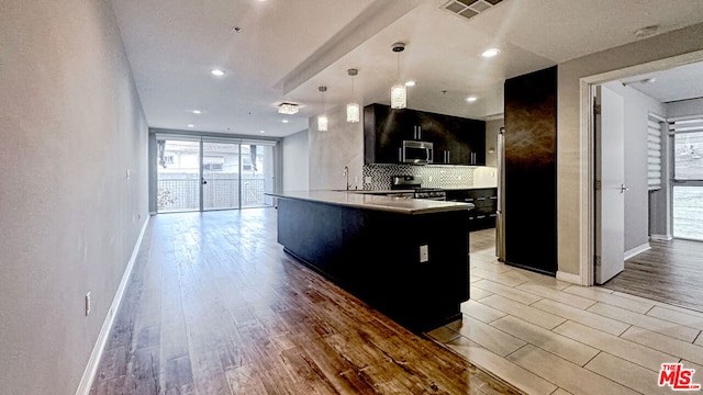 kitchen featuring stainless steel appliances, a center island, pendant lighting, and light hardwood / wood-style floors