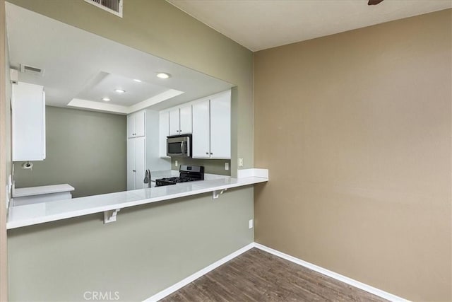 kitchen featuring stainless steel appliances, a breakfast bar, white cabinets, and kitchen peninsula