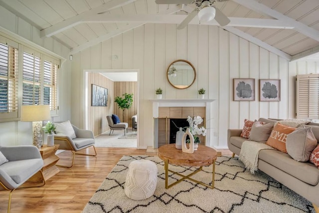 living room featuring ceiling fan, hardwood / wood-style floors, vaulted ceiling with beams, wooden walls, and a fireplace