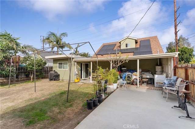 rear view of property with secured water heater, a lawn, and solar panels