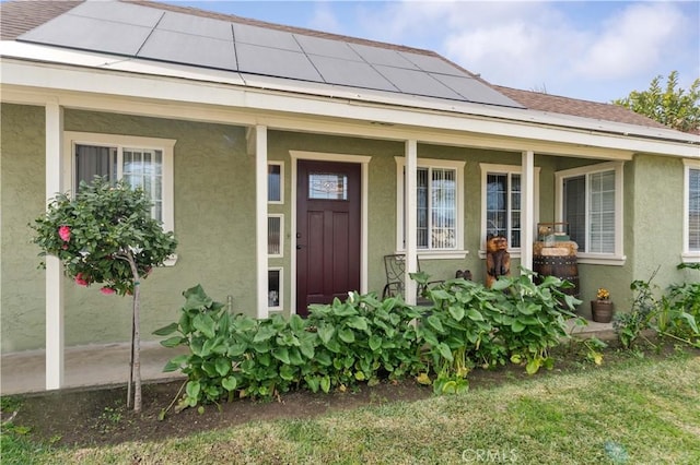 view of exterior entry with covered porch and solar panels