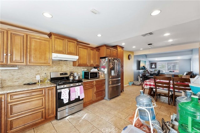 kitchen featuring appliances with stainless steel finishes, light stone countertops, and decorative backsplash