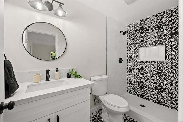 bathroom featuring vanity, tiled shower, and toilet