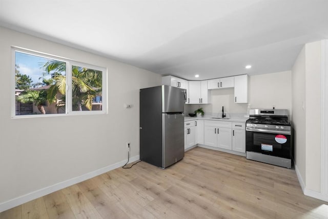 kitchen featuring sink, light wood-type flooring, white cabinets, and appliances with stainless steel finishes