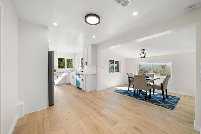 dining room featuring sink, light hardwood / wood-style flooring, and vaulted ceiling