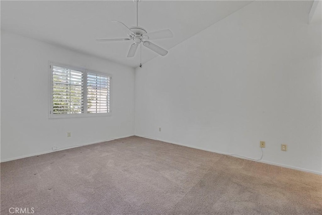 carpeted spare room featuring vaulted ceiling and ceiling fan