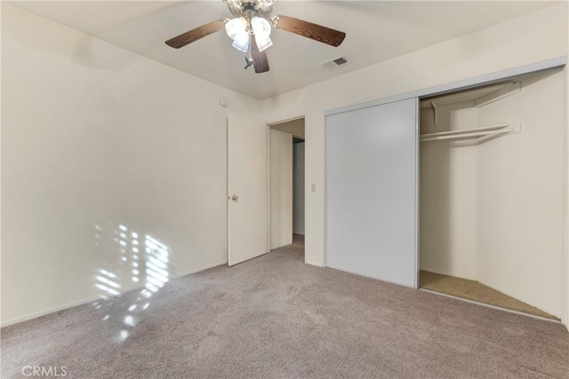 unfurnished bedroom featuring light colored carpet, a closet, and ceiling fan