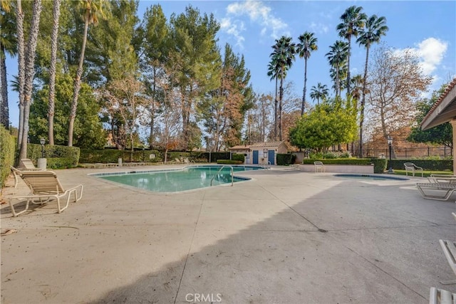 view of swimming pool featuring an outbuilding, a hot tub, and a patio