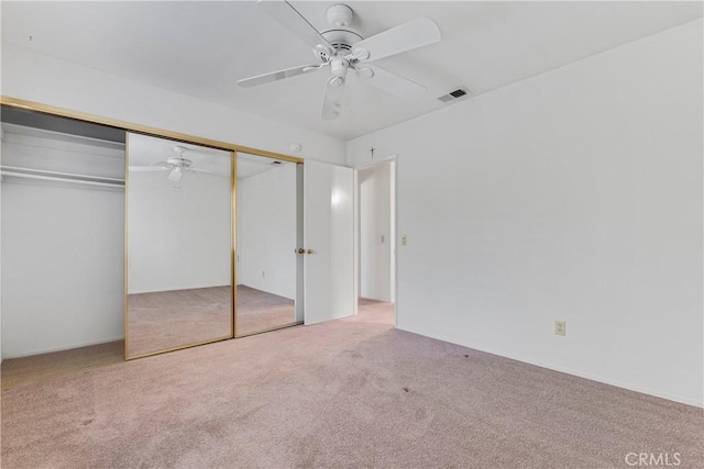 unfurnished bedroom featuring ceiling fan, light carpet, and a closet