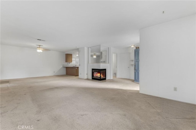 unfurnished living room with light carpet and ceiling fan