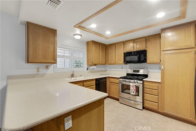 kitchen featuring a tray ceiling, kitchen peninsula, sink, and black appliances