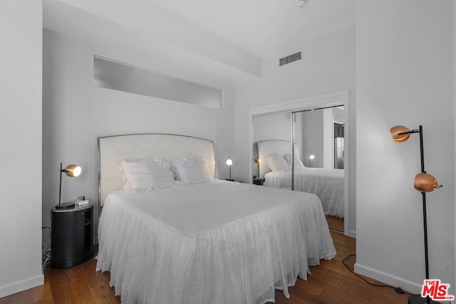 bedroom with dark hardwood / wood-style floors and a closet