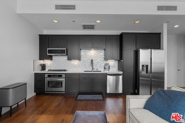 kitchen with sink, backsplash, dark wood-type flooring, and appliances with stainless steel finishes